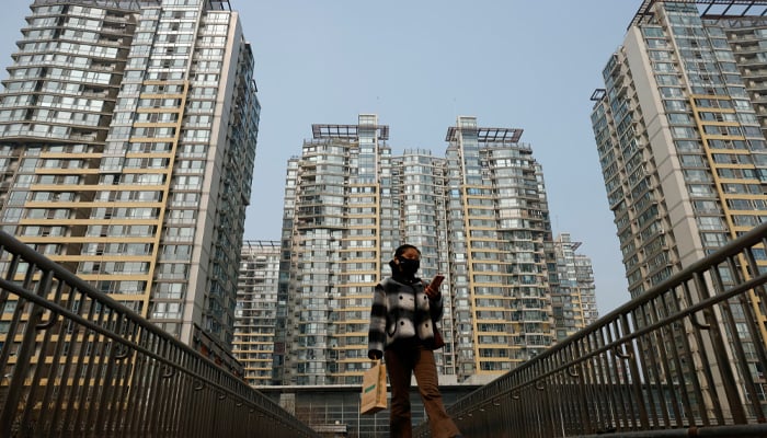 A girl walks amidst high-rise buildings in Beijing, China. — Reuters